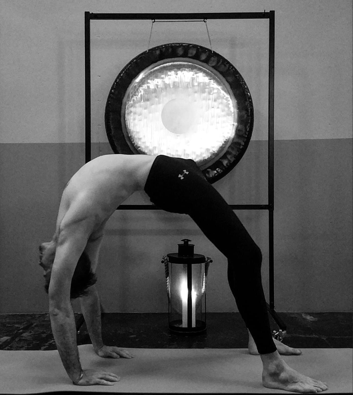 Gísli in a wheel pose in front of a gong